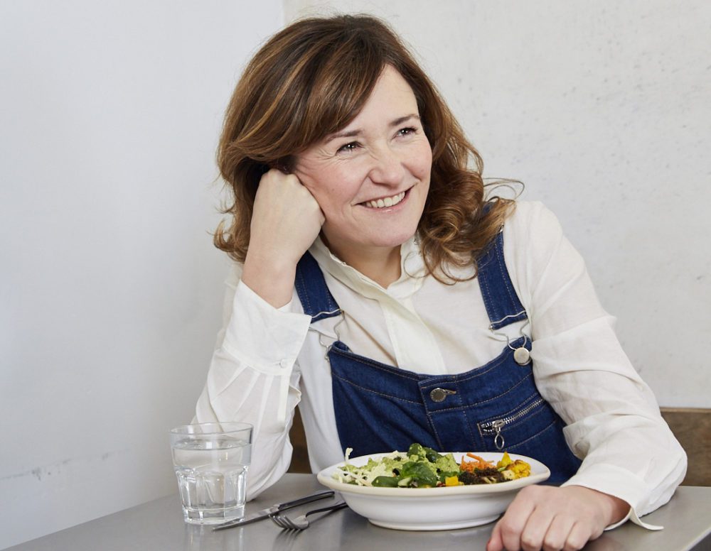Sam Bloom sitting at a table with her salad, created in collaboration with GAIL's Bakery